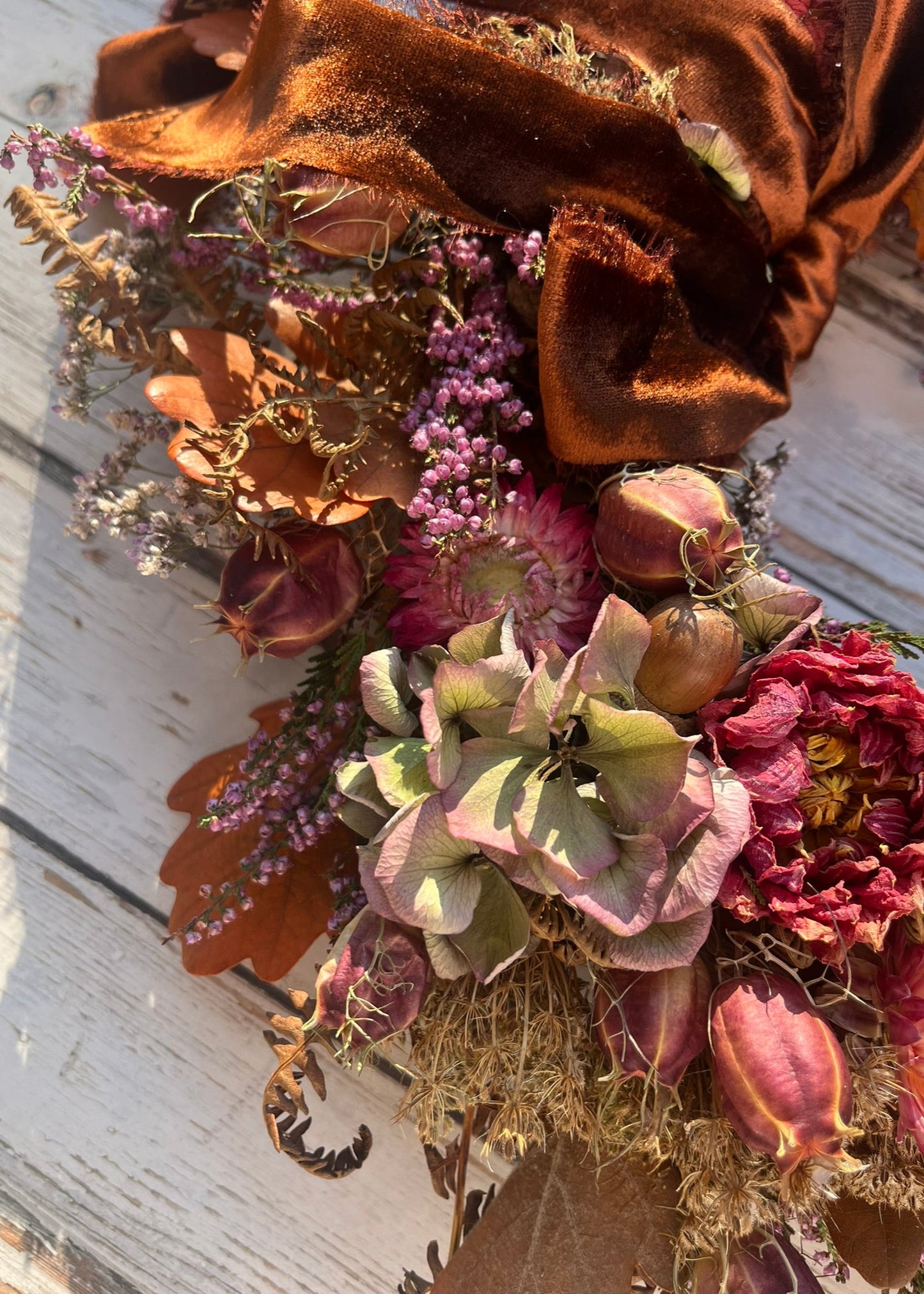 Bouquet of dried flowers with a large brown bow on a wooden surface