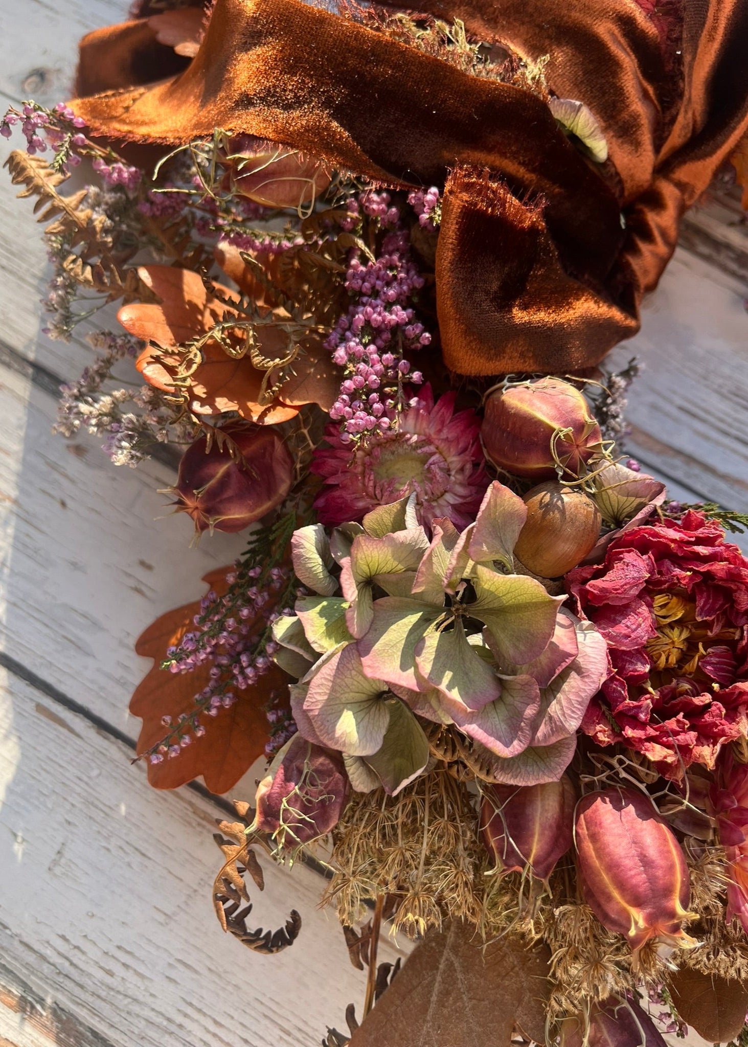 Bouquet of dried flowers with a large brown bow on a wooden surface