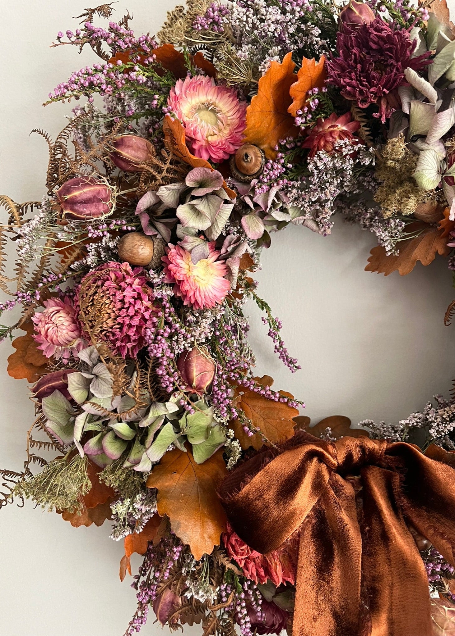 Decorative wreath with autumnal flowers and leaves on a white background
