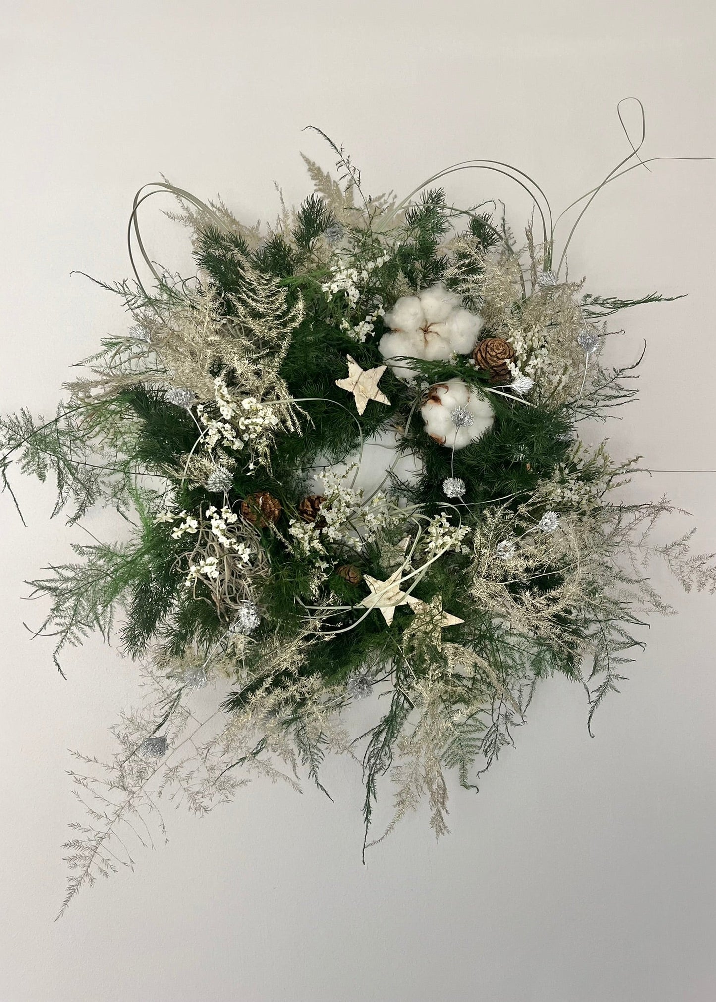 Decorative wreath with greenery, cotton, and stars on a light background