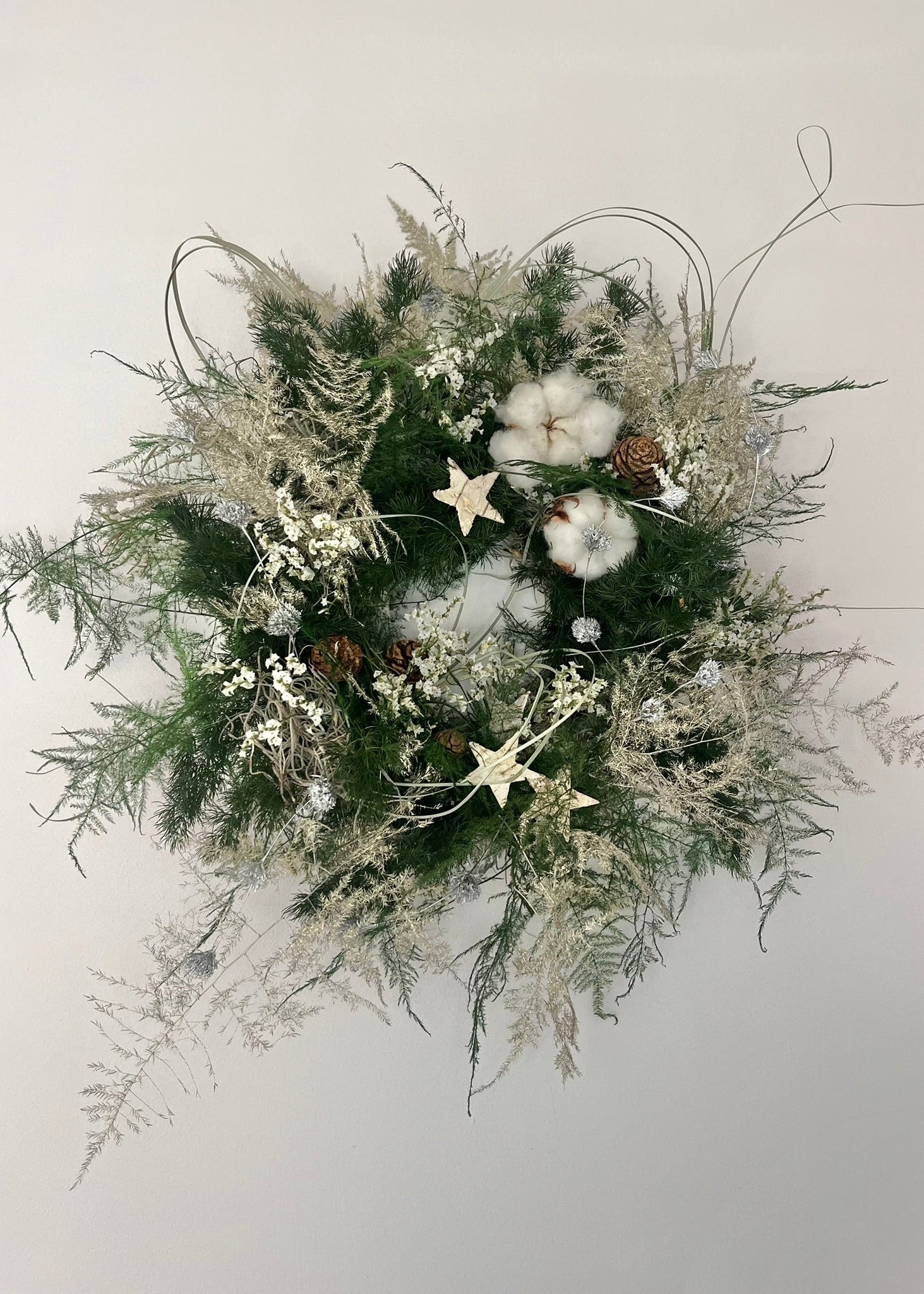 Decorative wreath with greenery, cotton, and stars on a light background