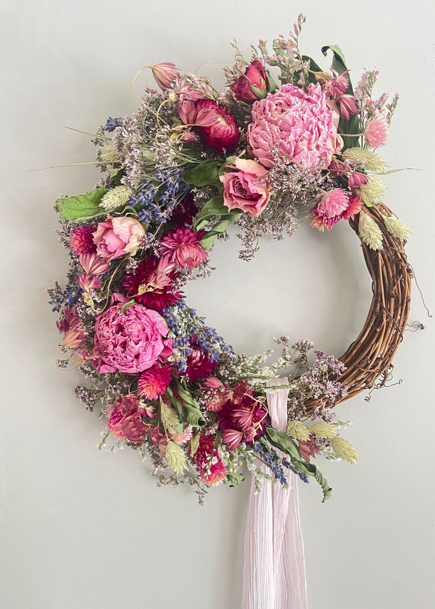 Floral wreath with pink and purple flowers on a white wall