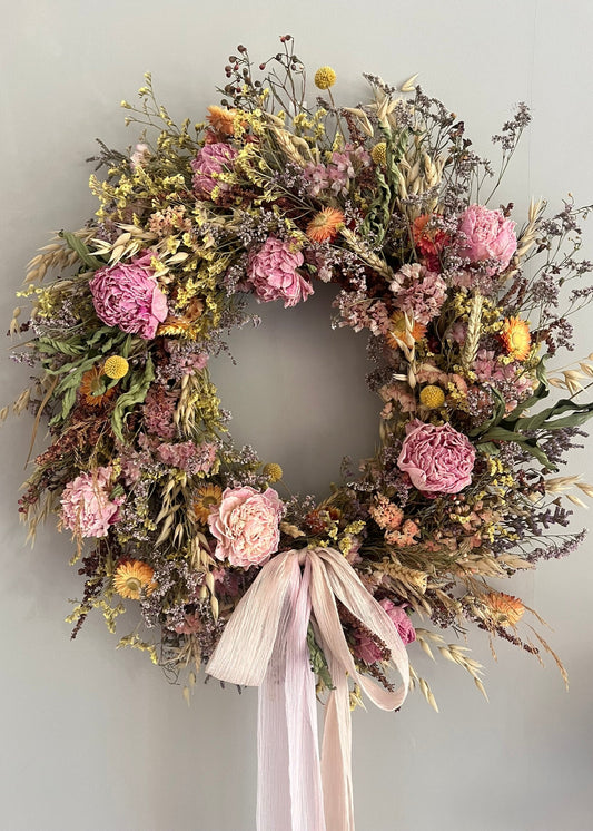 Floral wreath with pink flowers and green leaves on a plain background