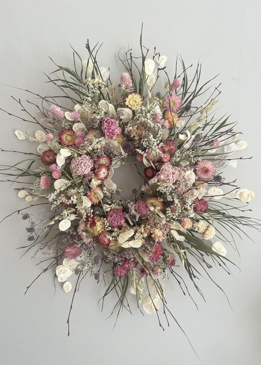 Floral wreath with pink, white, and green flowers on a gray background