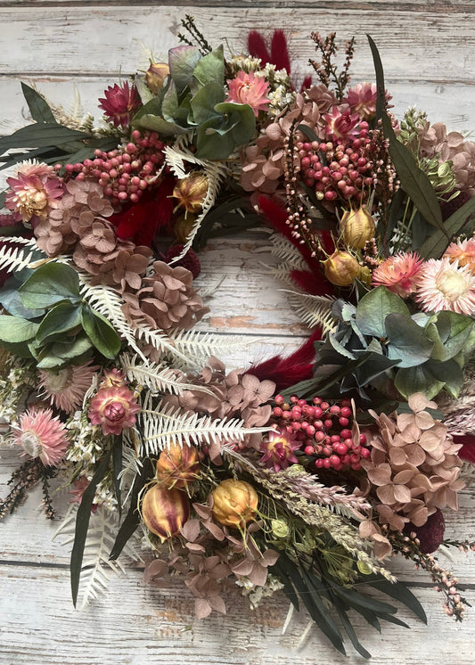 Floral wreath with pink and green flowers on a wooden surface