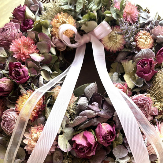 Floral arrangement with pink ribbon on a wooden surface