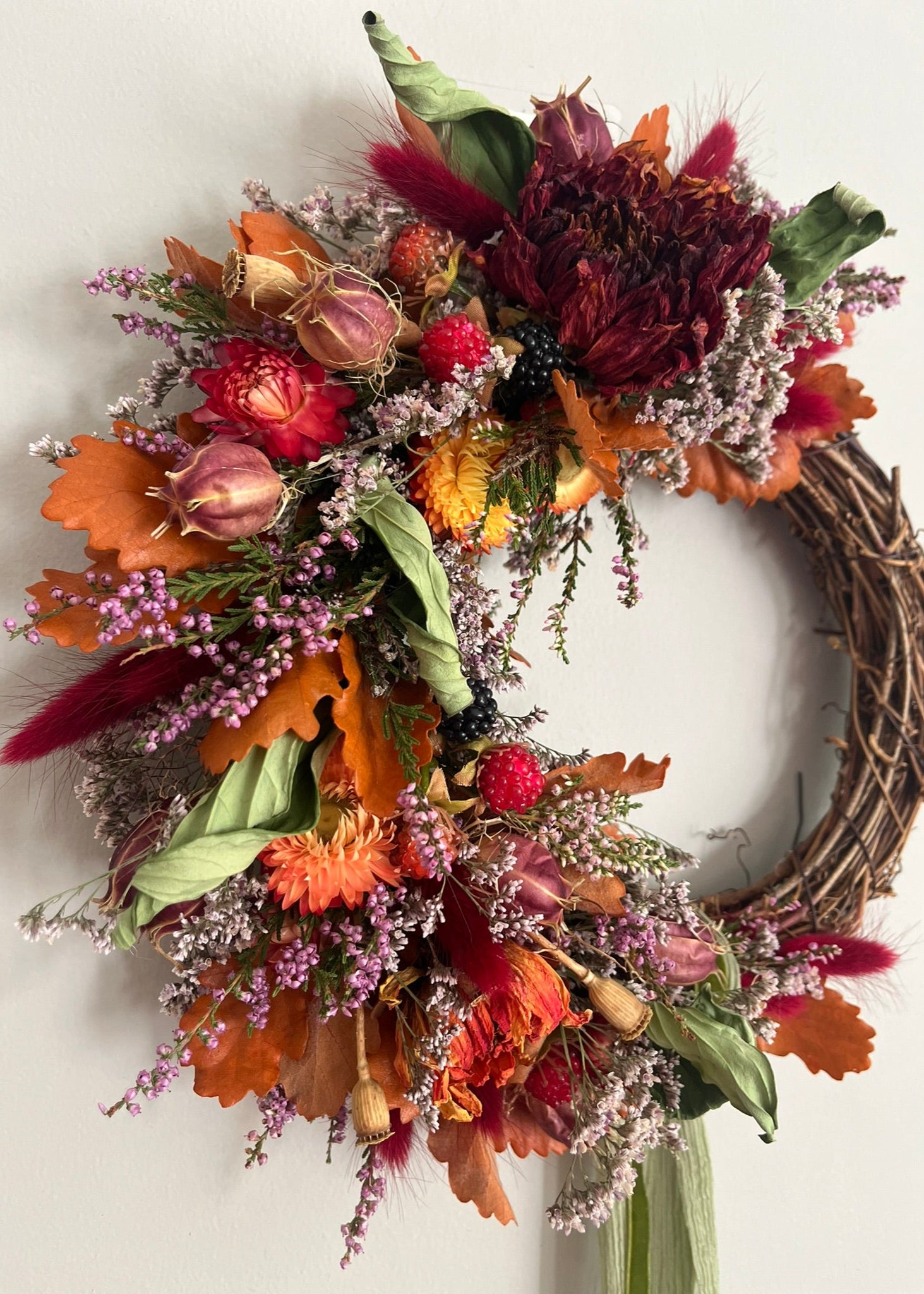Autumn-themed wreath with colorful flowers and leaves on a white background