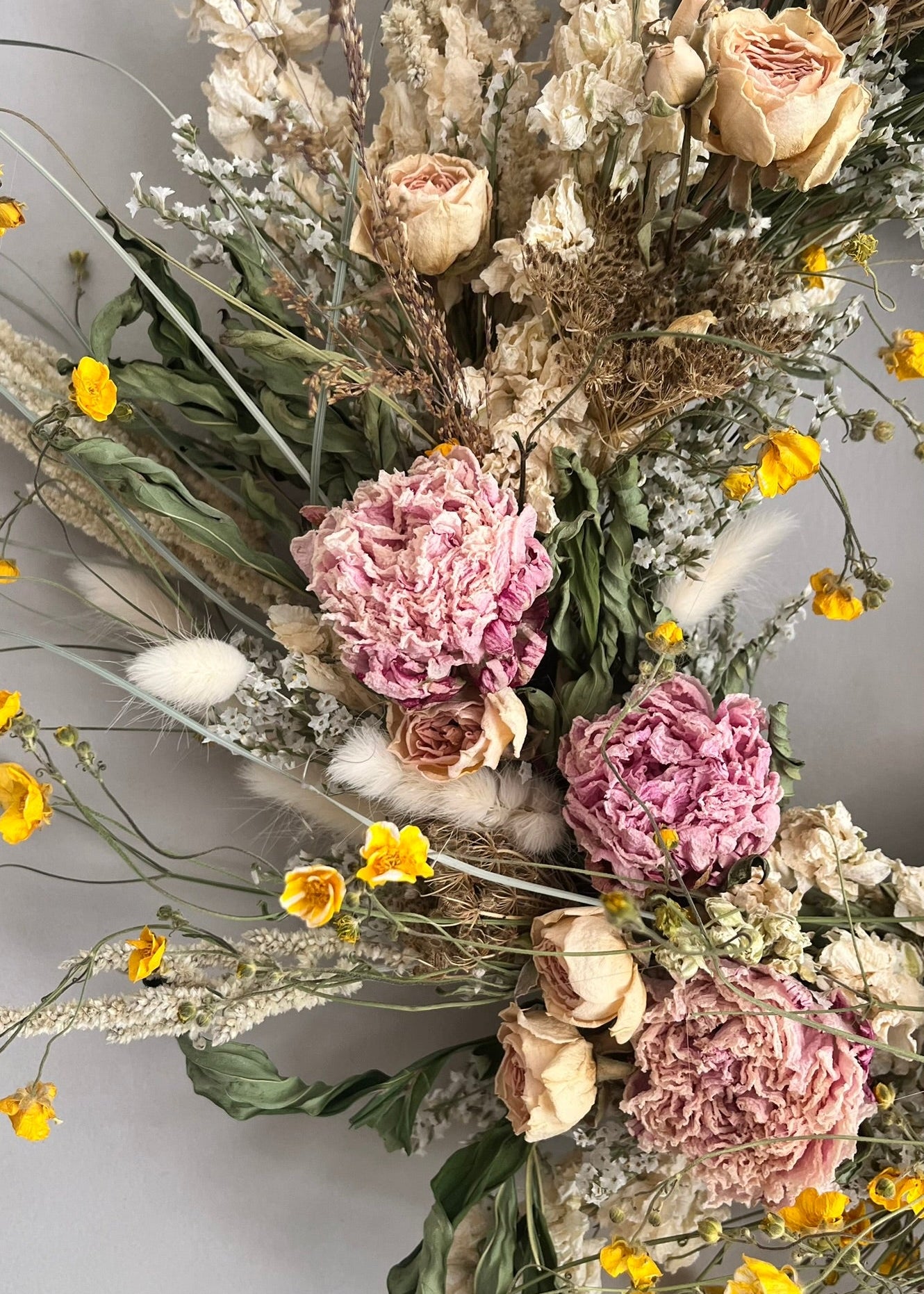 Bouquet of dried flowers with pink and yellow elements on a light background