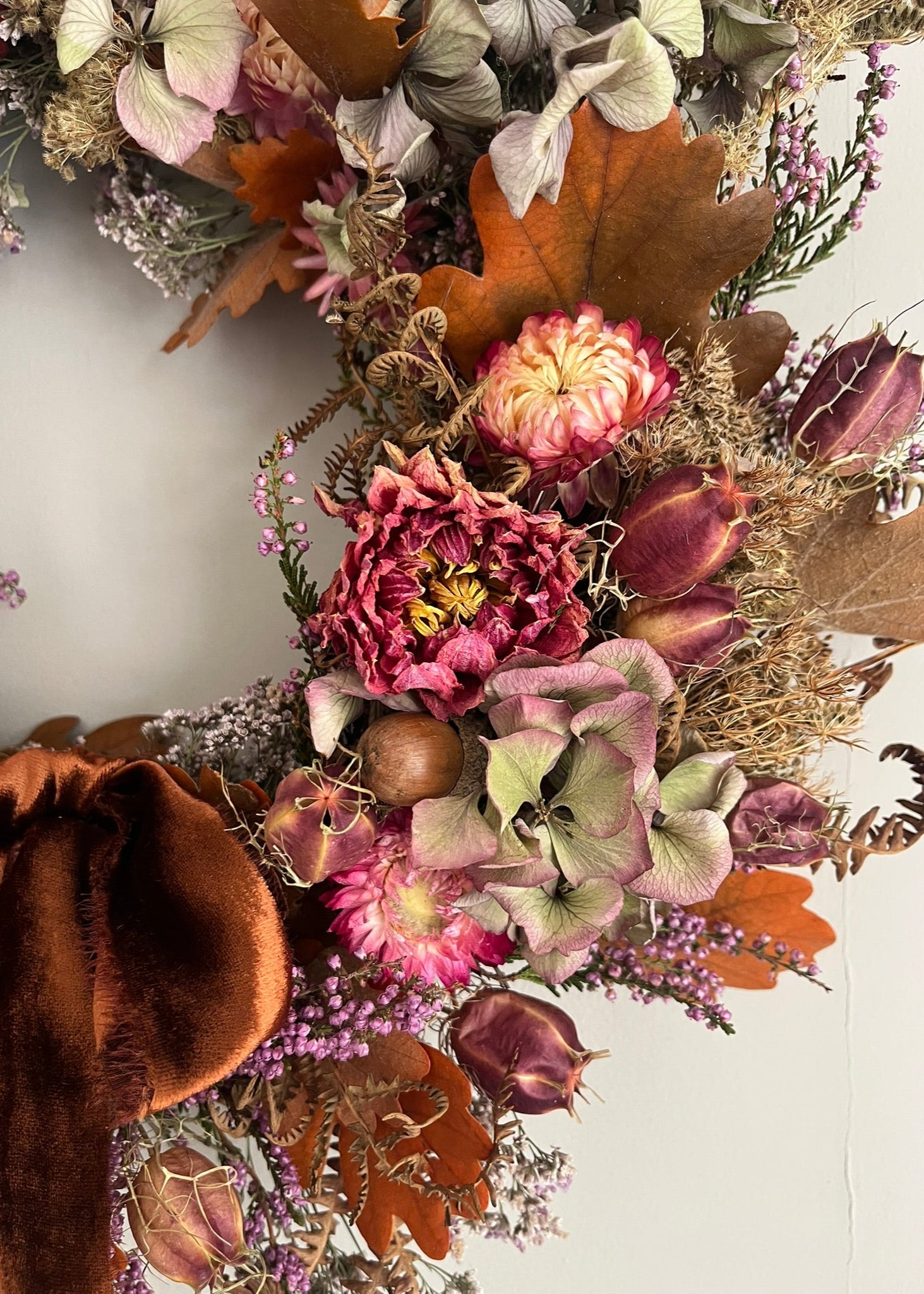 Autumnal floral arrangement with dried leaves and flowers on a white background