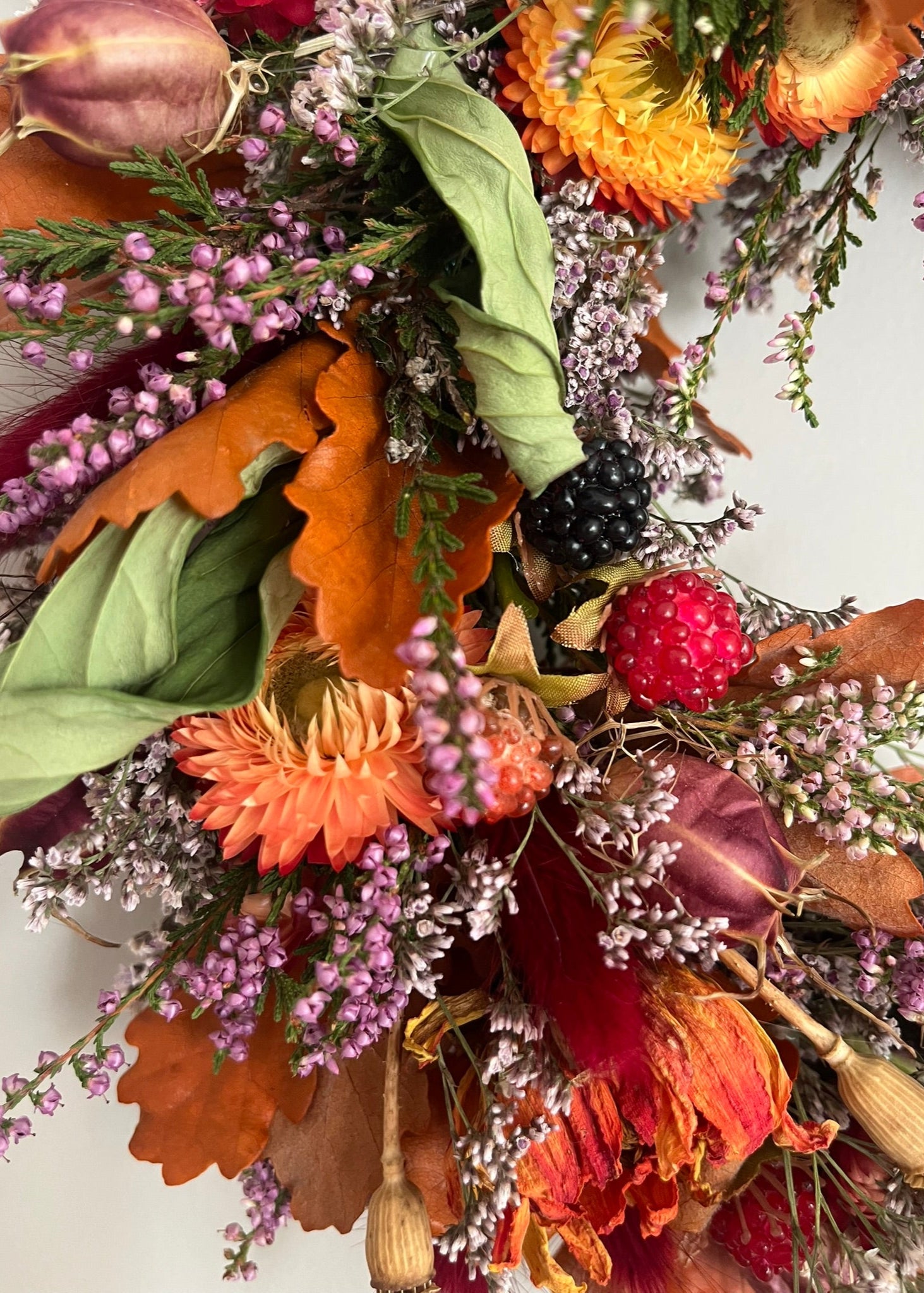 Decorative wreath with autumnal elements including leaves, berries, and flowers on a white background