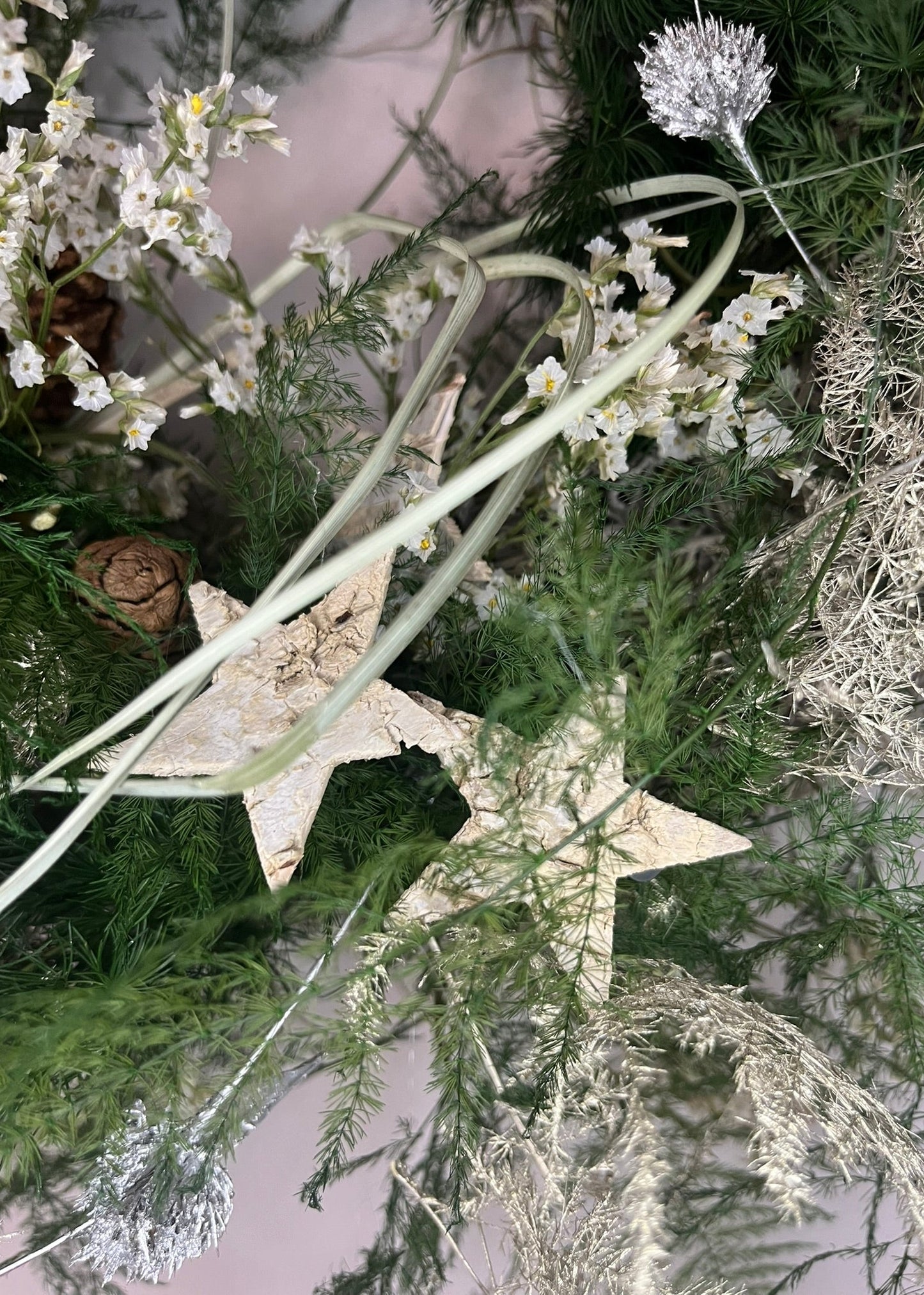 Decorative star ornament with greenery and white flowers on a neutral background
