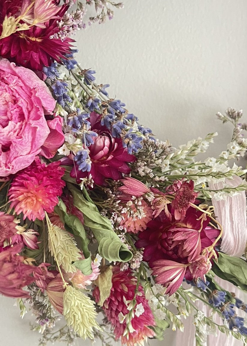 Floral wreath with pink and purple flowers on a light background