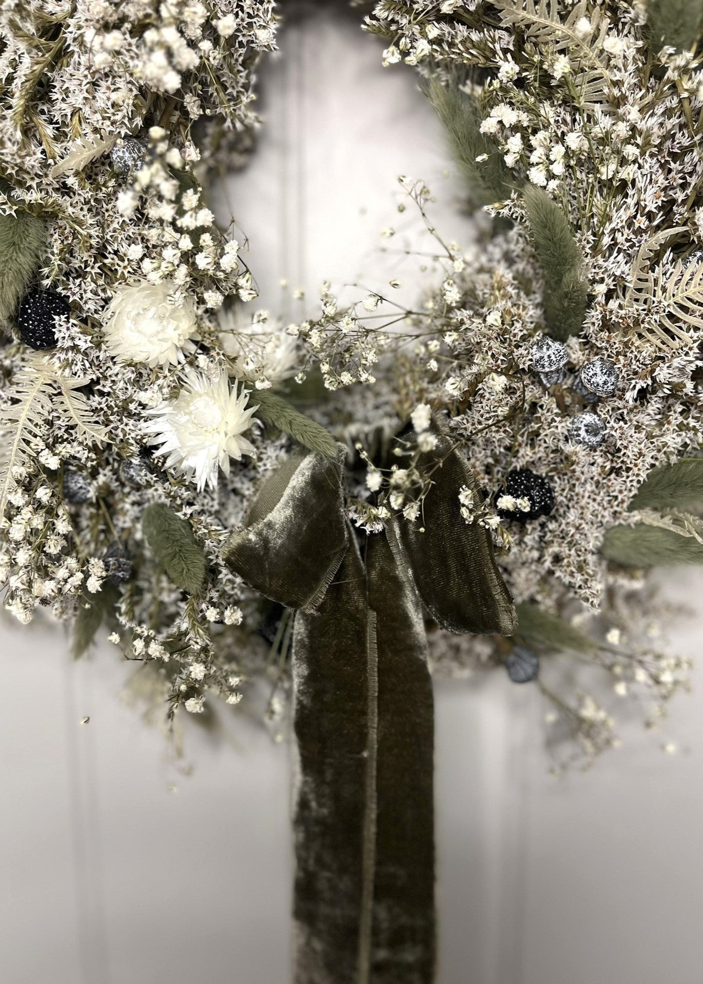 Decorative wreath with dried flowers and greenery on a white background