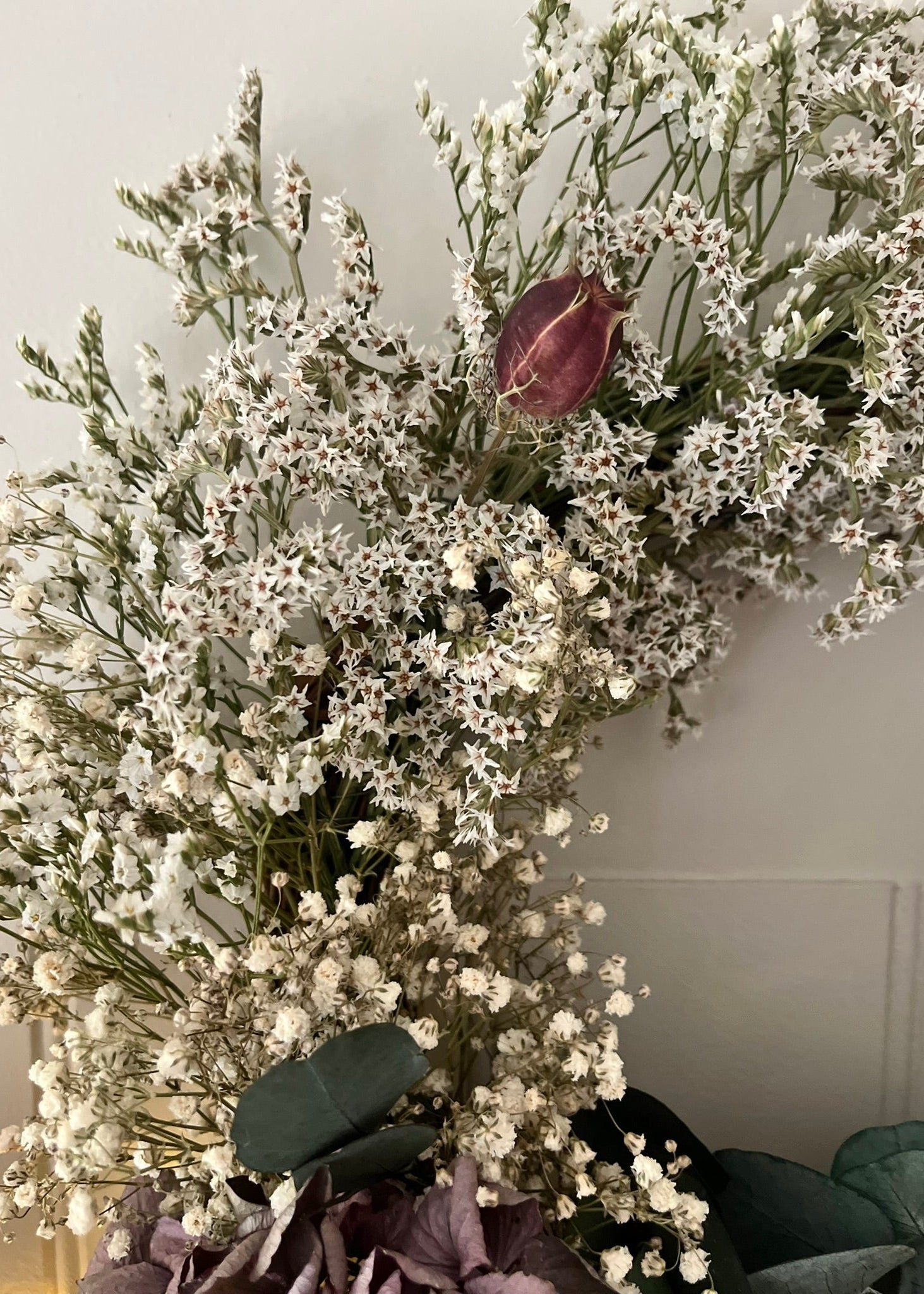 Decorative arrangement of white flowers and a purple flower against a neutral background