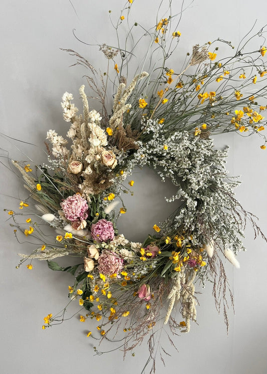 Decorative wreath with flowers and branches on a plain background