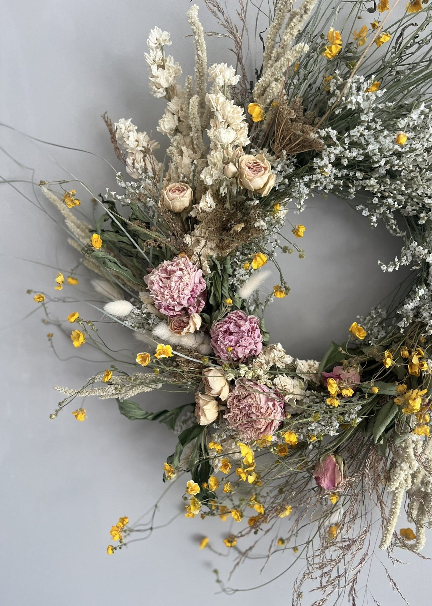 Floral wreath with dried flowers and pink flowers on a light gray background