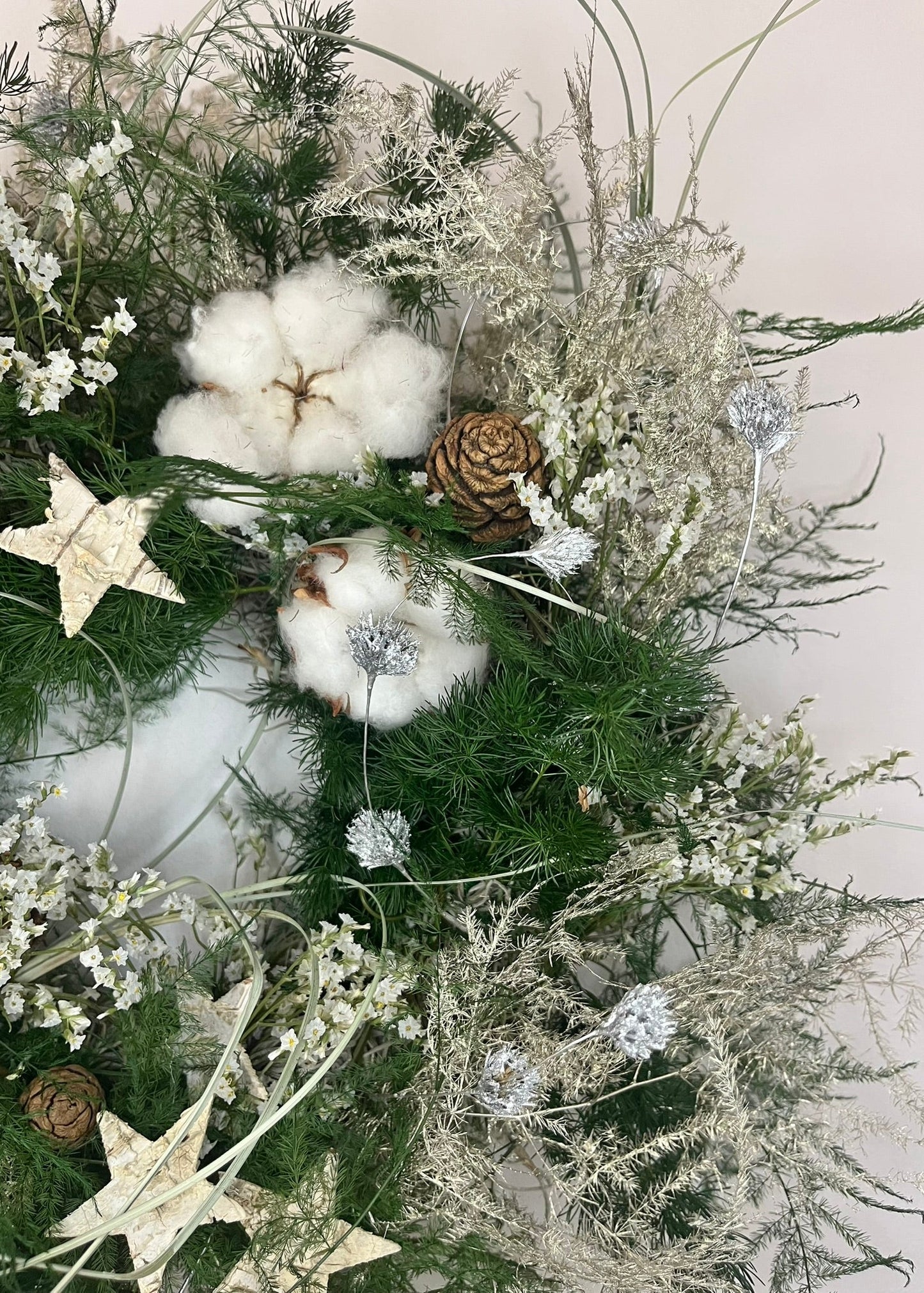 Decorative wreath with cotton, pinecones, and stars on a white background